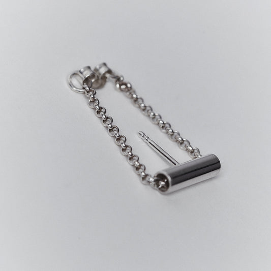 A silver earring with a chain running through a tube.