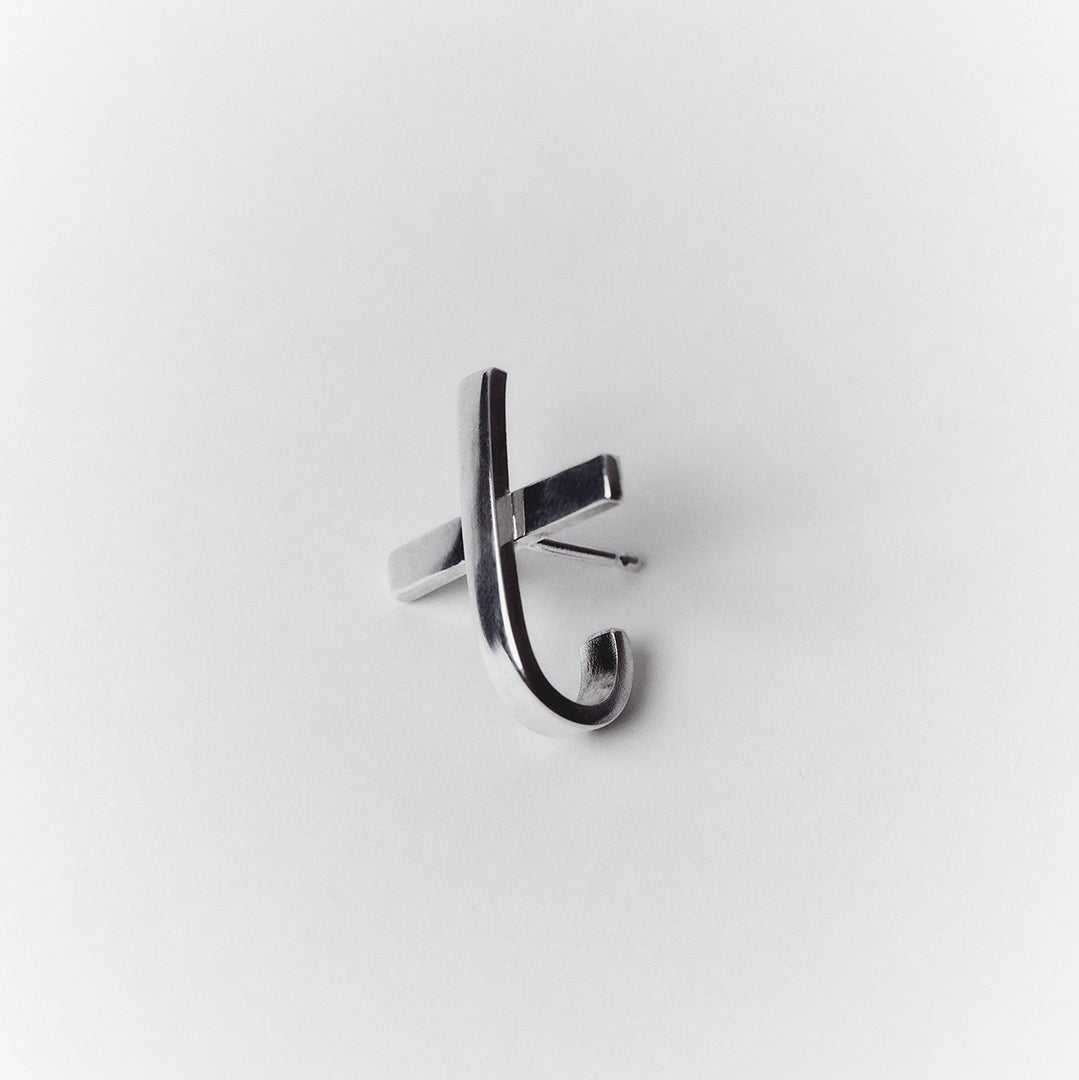 An x or cross shaped silver earring with a hoop that hugs around the earlobe.