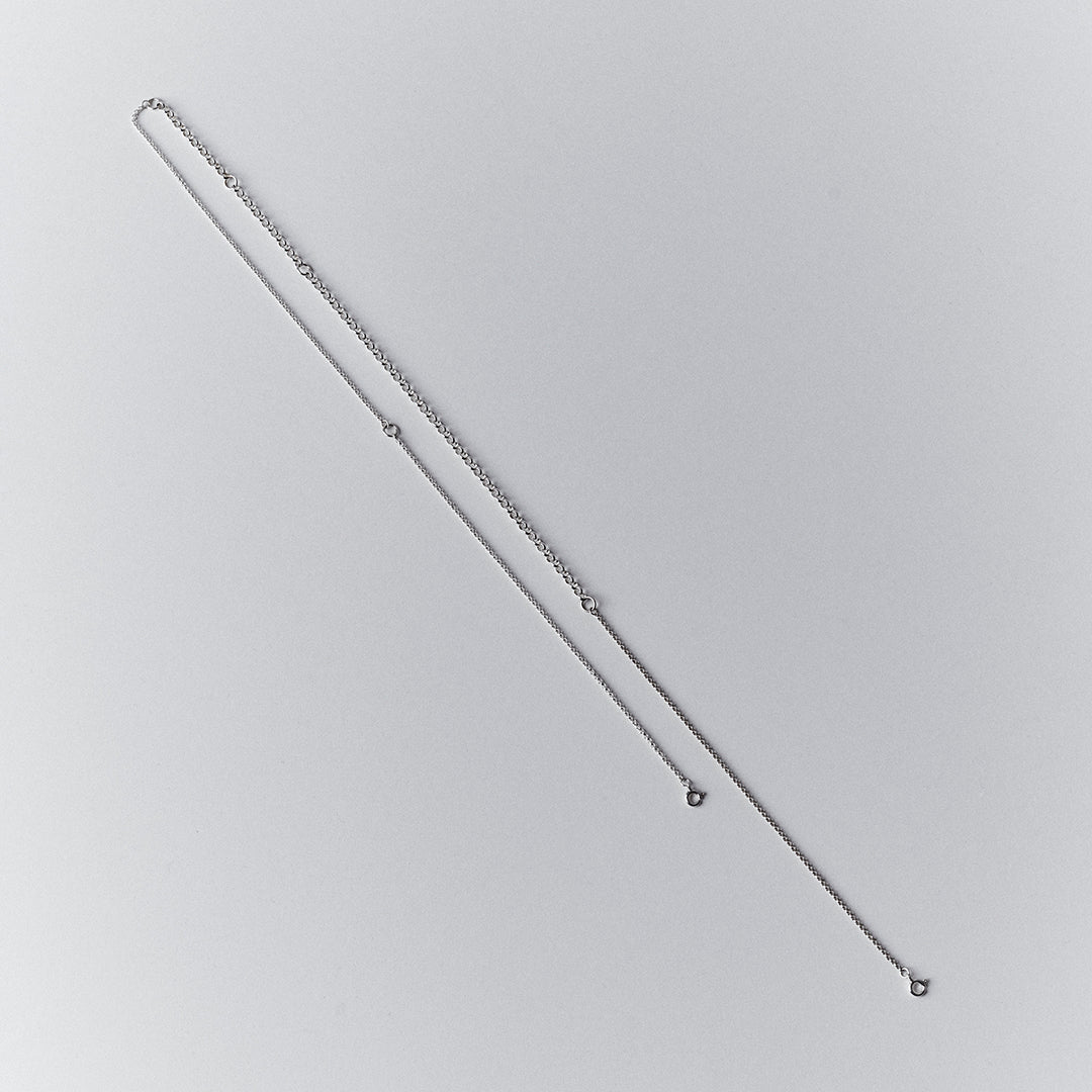 A long silver chain with thicker and thinner segments and two clasps.