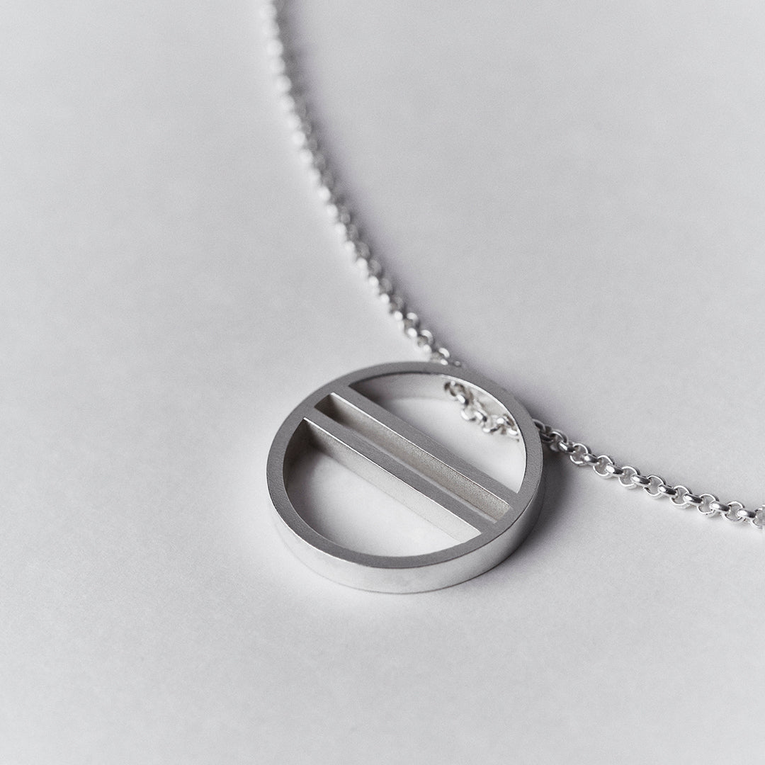 Detail zoom in of a silver necklace with an equality symbol pendant.