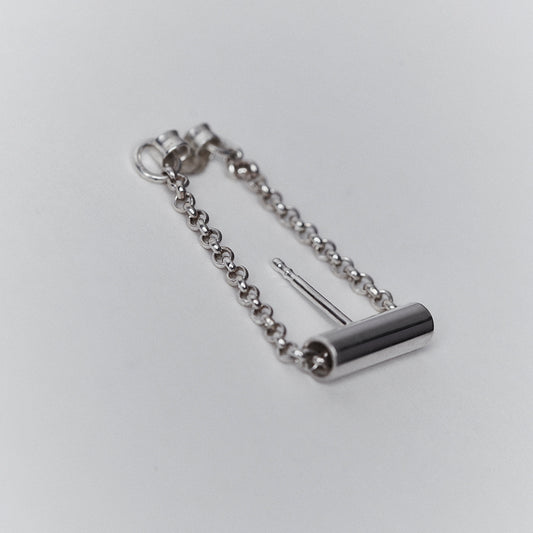 A silver earring with a chain running through a tube. 