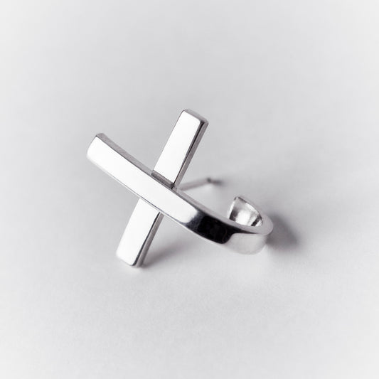 An x or cross shaped silver earring with a hoop that hugs around the earlobe.