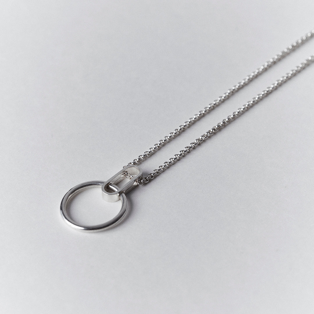 A silver necklace with an oval shape collected to a thick ring.