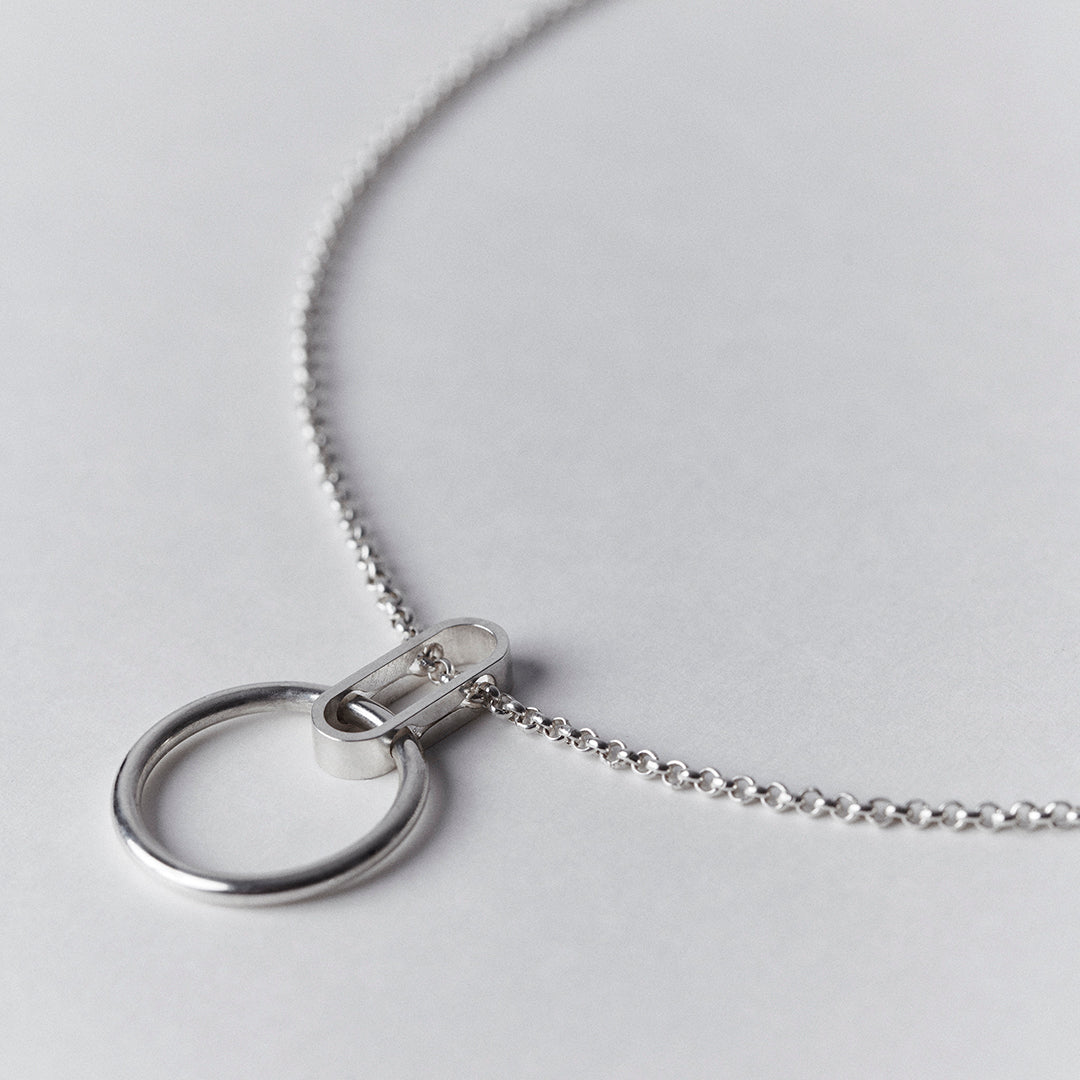 A silver necklace with an oval shape collected to a thick ring.