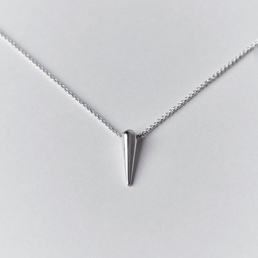 A woman's cheA silver chain and a silver spike shaped pendant. 