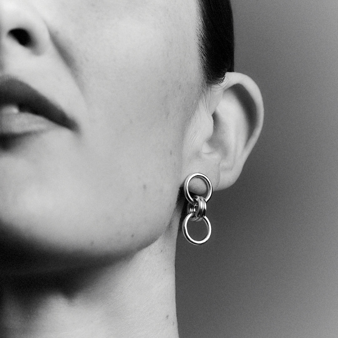 woman wearing a bold silver earring with a double ring.