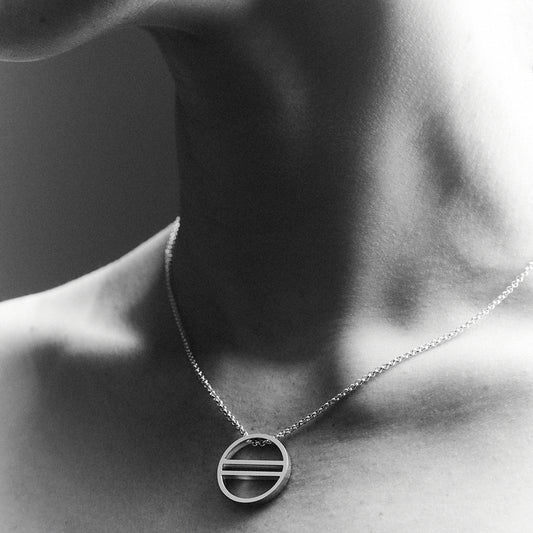 Woman's neck wearing a silver necklace with an equality symbol pendant. 