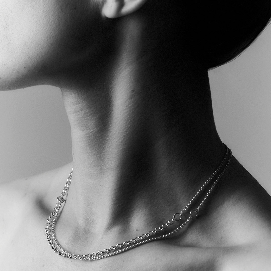 A woman's neck profile showing a double layered silver necklace.